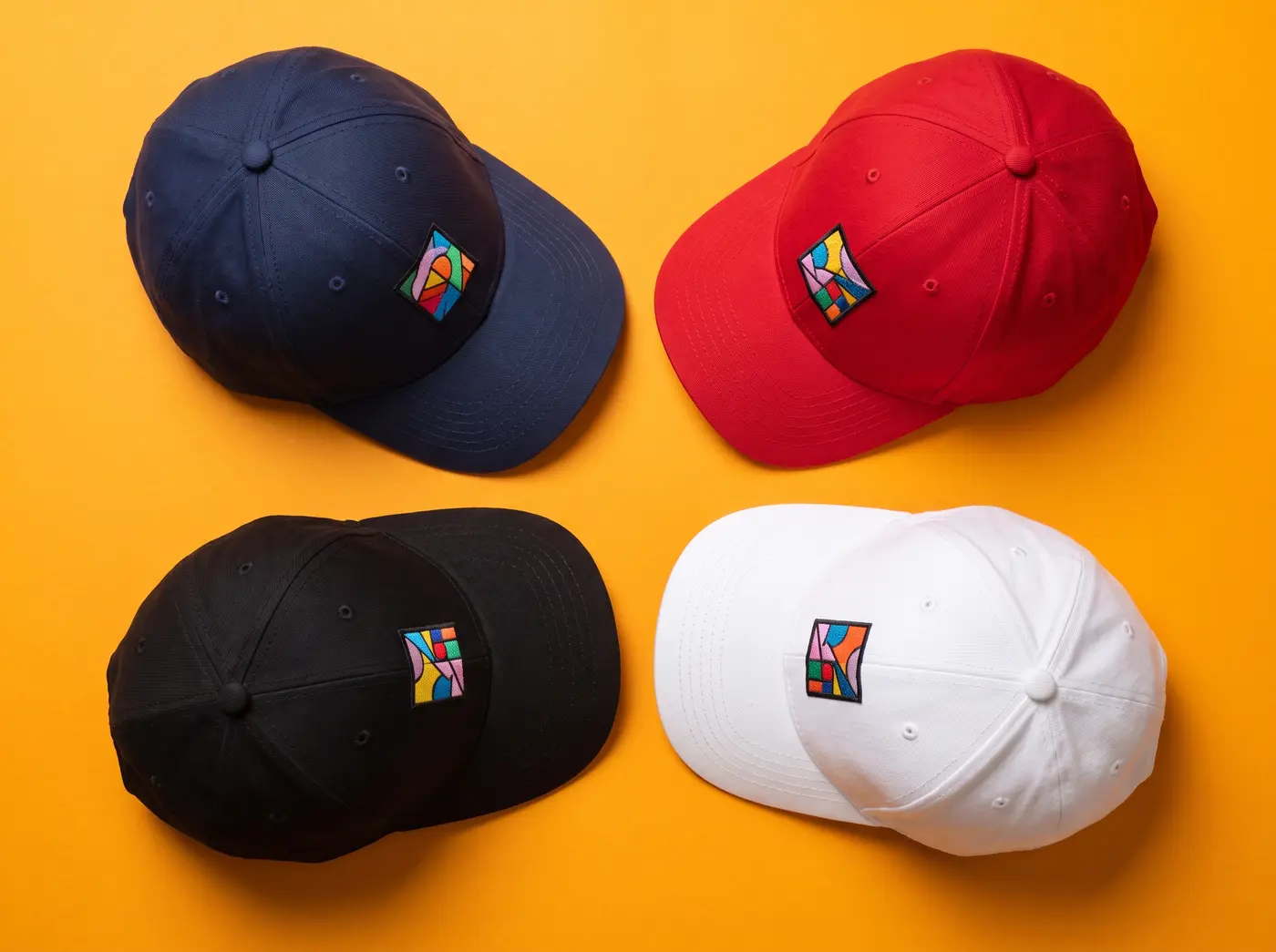 Quatre casquettes imprimées en marine, rouge, noir et blanc sur fond orange